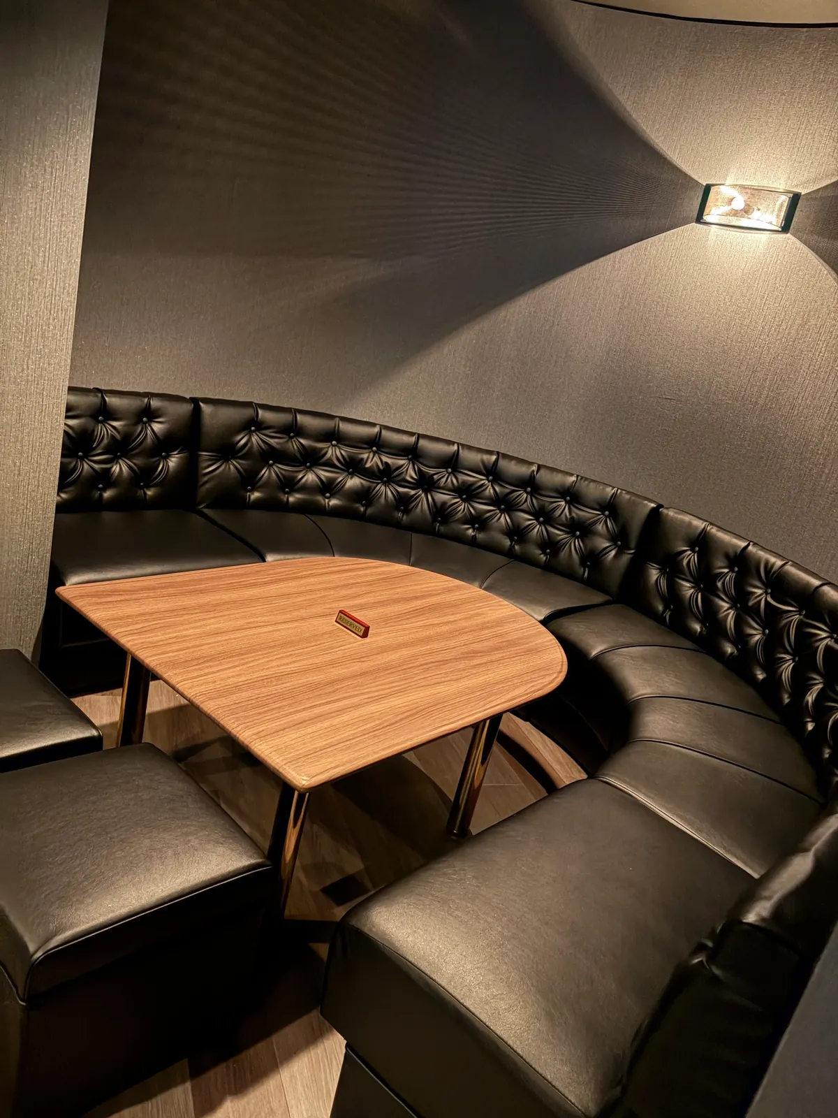bar KURAXの黒いソファ席と木目のテーブル